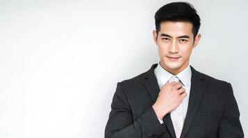 Asian man in suit adjusting tie photo