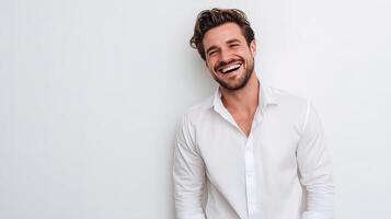 A man is smiling while standing in front of a white wall photo