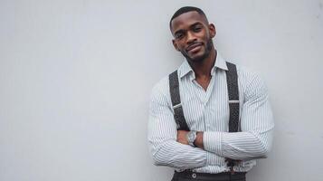 A man in a shirt and suspenders standing against a wall photo