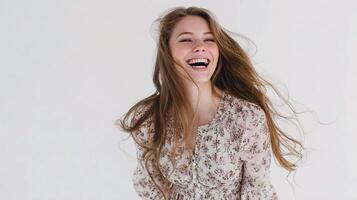 A woman is laughing while standing in front of a white background photo