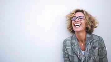 A woman with glasses and a checkered jacket is laughing photo