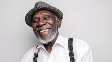 An older man with a hat and suspenders smiling photo