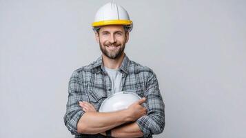 Portrait of smiling male construction worker holding a helmet isolated on white background photo