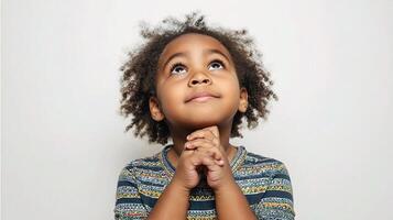 A young child is looking up with his hands on his chin photo