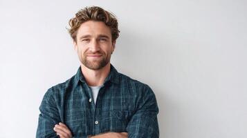 A man with his arms crossed standing in front of a white wall photo