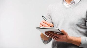 A man is holding a pen and writing on a notepad photo