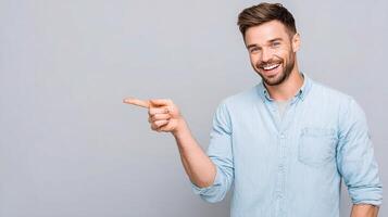 Smiling man pointing at something on a gray background photo
