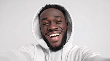 A man in a hoodie smiling and taking a selfie photo