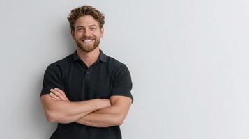 A man with a beard and a smile is standing in front of a white wall photo