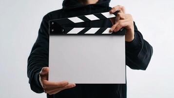 A person in a hoodie holding a clapper board photo