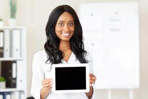 Happy black businesswoman demonstrating tablet computer with empty screen at company office, mockup for website or app design. Confident female manager with touch pad, space for advertisement photo