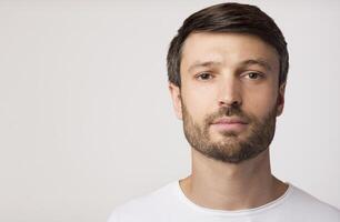 Portrait Of Confident Man Looking At Camera Posing Over White Studio Background. Copy Space photo