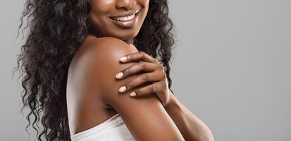 Spa procedures for body. Unrecognizable black woman enjoying her smooth soft skin over grey background, panorama with empty space photo