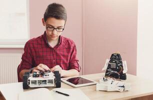 Concentrated boy creating robot at lab. Early development, diy, innovation, modern technology concept. Stem education. photo