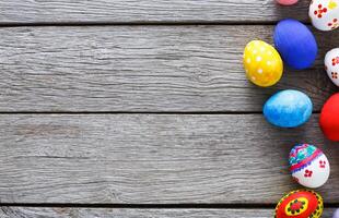 Easter eggs on wood background. Colorful handmade painted eggs on rustic table top view with copy space photo