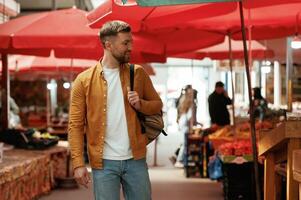 Going forward, looking at products. Handsome man is on the street market or bazaar photo