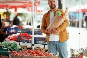 Collection of products, in paper bag. Handsome man is on the street market or bazaar photo