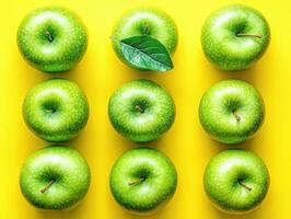 Fresh green apples arranged in a pattern on a bright yellow surface photo