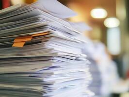 Piles of documents stacked on a desk in a busy office environment photo