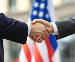 Handshake between officials in front of flags representing nations photo