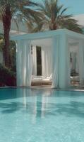An idyllic outdoor lounge area featuring a luxurious cabana by the swimming pool during daytime photo