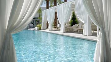 Serene turquoise waters of a luxury resort pool with elegant white curtained cabanas creating a peaceful scene photo
