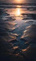 Golden hour paints the wet sand in warm tones as the sun dips below the horizon at dusk photo