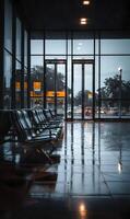 Sleek metal chairs stand in an empty lobby, reflecting the outside world on a rainy day photo