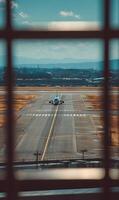 Plane preparing for take off on the runway viewed through a grid window framing the scenery photo