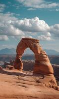 Majestic Delicate Arch standing tall against a scenic Utah sky with mountain backdrop photo