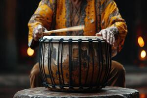 Man plays musical percussion instrument with sticks closeup on a black background, a musical concept with the working drum, beautiful lighting on the stage photo