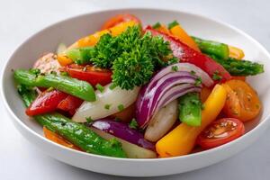 Colorful salad with tomatoes, onions, peppers, asparagus and parsley resting in white bowl photo
