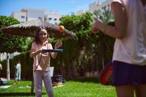 Children Playing Paddleball Outdoors in a Green Park on a Sunny Day photo