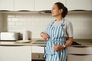 Woman in Apron Standing in Modern Kitchen Setting photo