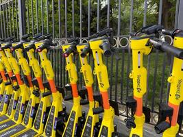 Moscow, Russia, April 24, 2025. Branded Yandex Go scooters neatly parked in row along fence, symbolizing modern eco transport, urban mobility and growth of micro mobility services in big cities photo