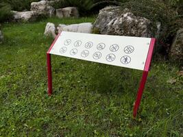 Prohibition sign in a public park with visual icons indicating restricted activities such as cycling, fishing, and littering. Clear visual design promotes safety and respectful park use photo