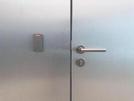 Closed metal office door with smart card reader and secure handle. Symbol of corporate access control, staff only zones, modern building security and workplace infrastructure photo