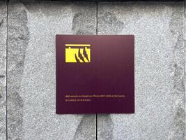Warning sign with minimalist graphic of claws mounted on stone wall, cautioning visitors against climbing over barrier in area with wild animals, combining safety message with clean modern design photo