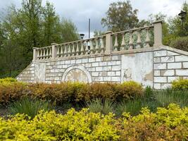 Restoration of a balustrade and stone wall with staircase in a public park, showing peeling paint and renewed landscaping as part of ongoing park improvement and renovation efforts photo