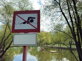 Close up of a safety sign by the pond with a clear prohibition of swimming. The warning is part of public safety measures in recreational park areas with water access photo