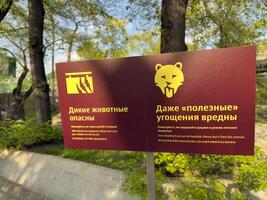 Close up of bilingual signs in Russian zoo warning not to feed animals or place children on the barrier. Clear pictograms emphasize danger and safety for visitors photo