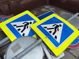 Decommissioned pedestrian crossing signs stacked on the ground as part of an urban infrastructure update. Symbolic representation of modernization and street renovation in the city photo