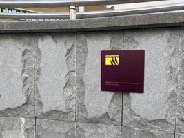 Modern warning plaque with claw icon mounted on smooth gray granite wall, blending visual clarity with bold contrast to deliver safety message through simple graphic language in public environment photo