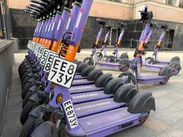 Moscow, Russia, April 24, 2025. Close up of branded electric scooters lined up for rent on city sidewalk, emphasizing license plates and urban micro mobility solutions in public spaces photo