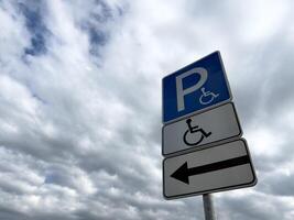 Handicap parking sign with directional arrow on cloudy day, indicating accessible parking for people with disabilities, promoting inclusion and barrier free infrastructure photo
