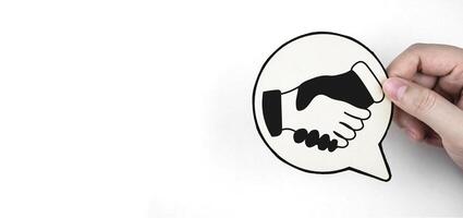 Hand holding paper with hand shake icon. Concept of cooperation, business or education networking and investment deal. With copy space. photo