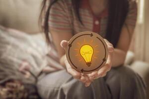 Woman holding a circle paper with light bulb icon. Represents new idea generation, design thinking, creative process and complex problem solving. photo