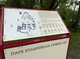 Moscow, Russia, April 25, 2025 Closeup of bilingual information stand at Huamin Park in Moscow shows detailed layout map and list of rules in Russian and Chinese with symbolic icons photo