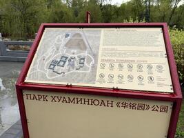 Moscow, Russia, April 25, 2025 Informational board with map and visitor rules at Huamin park in Moscow, designed in Chinese style and placed near scenic landscape and traditional architecture photo