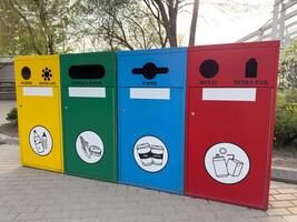 Modern waste sorting bins in an eco friendly urban environment. Yellow, green, blue, and red containers encourage proper recycling and waste management in public spaces photo